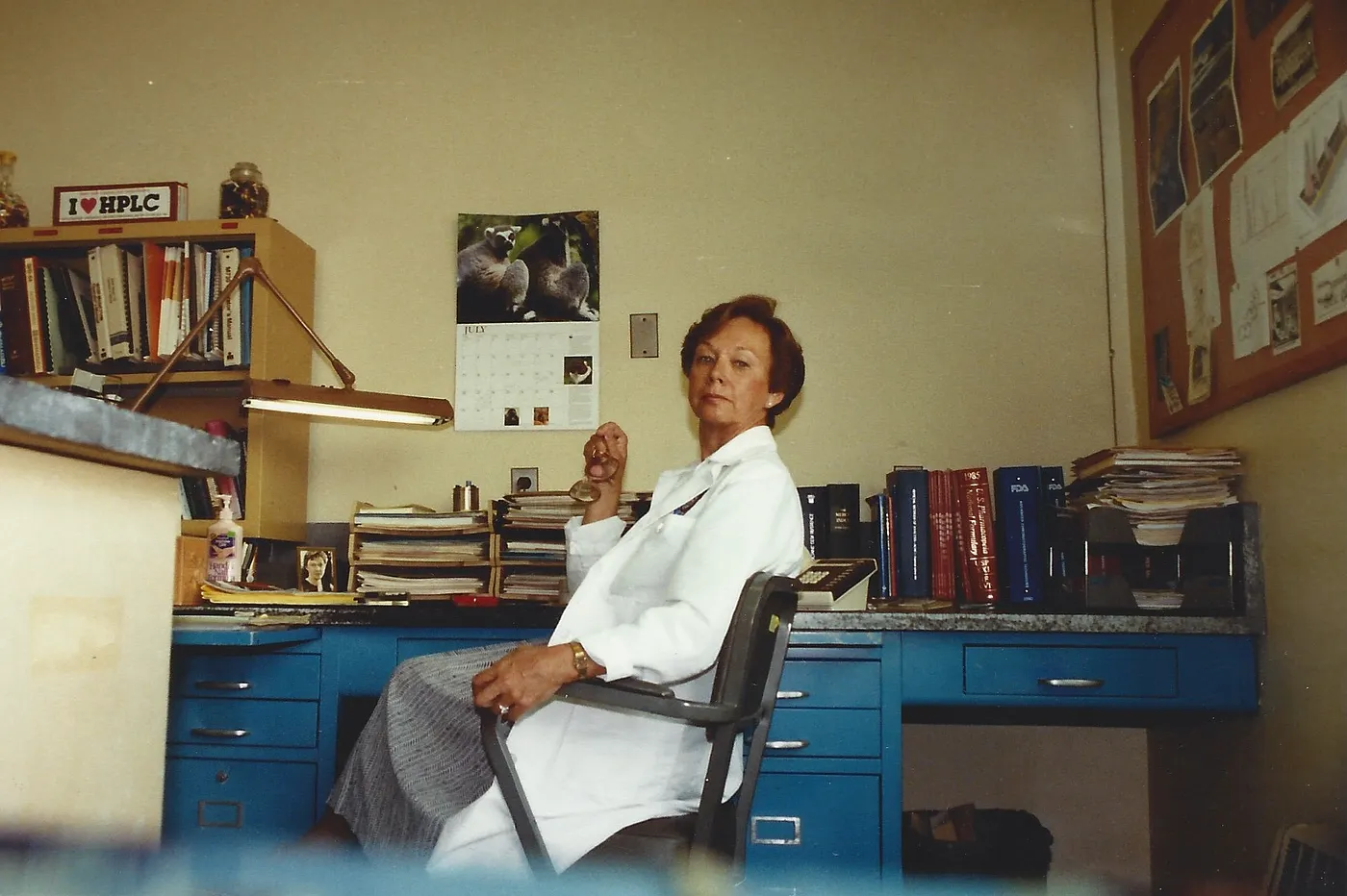 My grandmother seated at her desk in a laboratory, wearing a white lab coat